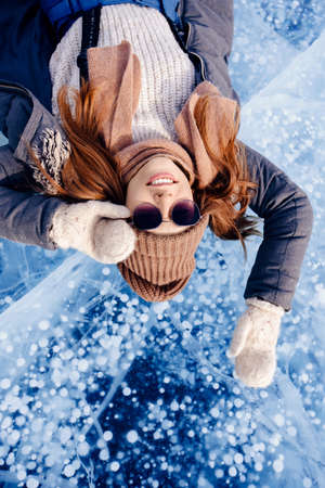Travel winter Lake Baikal, happy joy woman tourist lie on ice sunset, top viewの写真素材