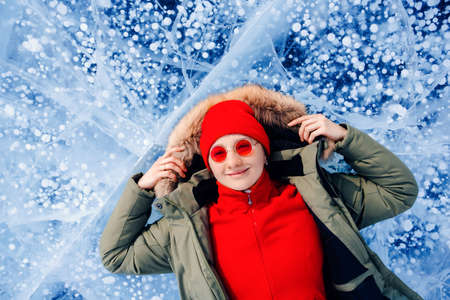 Travel winter Lake Baikal, happy joy woman tourist lie on ice sunset, top viewの写真素材