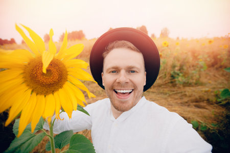 Smile young farmer man in hat in sunflowers field. Sunlight concept lifestyle summer happy