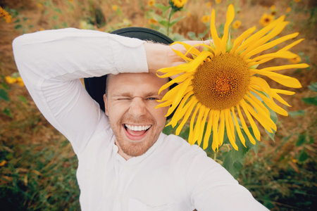 Smile caucasian farmer worker man in hat in sunflowers field sunlight. Concept lifestyle summer...