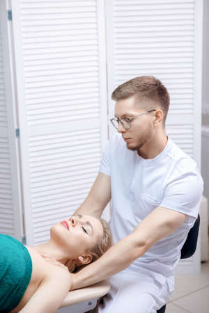 Doctor osteopath performs sports massage neck muscle therapy for young woman athlete after workoutの写真素材