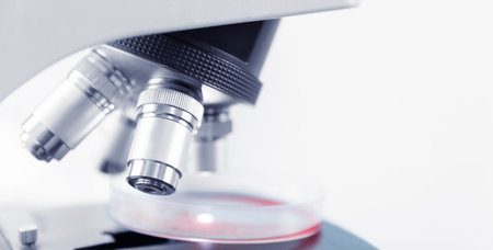 Macro microscope at laboratory analyzing blood, banner white light blue color toning