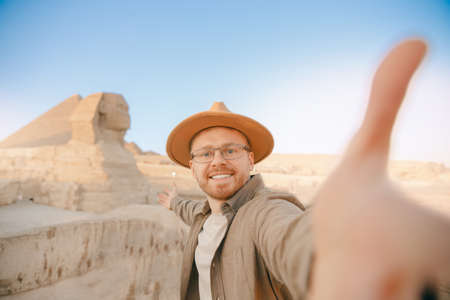 Travel Selfie photo man in hat background pyramid of Egyptian Giza and Sphinx, sunset Cairo, Egypの写真素材