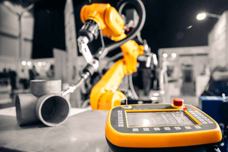 Closeup yellow arm robot welding metal pipe part in industry factoryの写真素材