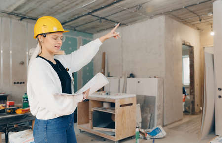 Foreman designer woman inspecting work of builder construction in apartment, checks supervision design project conceptの写真素材