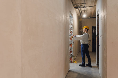 Designer woman checks author supervision builder work in apartment and compares design project with drawingsの写真素材