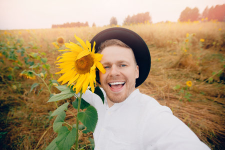 Smile young farmer man in hat in sunflowers field. Sunlight concept lifestyle summer happy