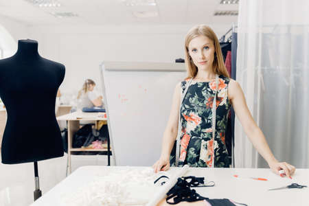 Happy young woman teacher of sewing courses for seamstress on background chalkboard patterns for sewsの写真素材