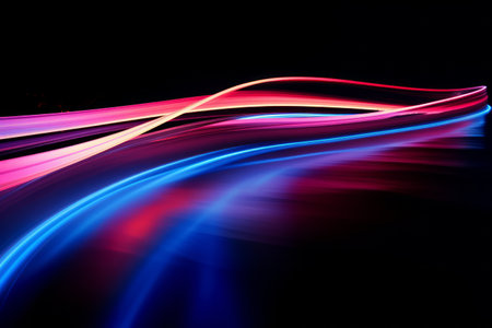 Long exposure of colorful light trails in motion on a dark background.の素材