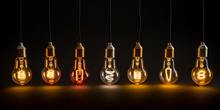 Various styles of glowing filament light bulbs against a dark backgroundの素材