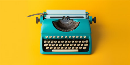 Vintage turquoise typewriter on a yellow background.の素材