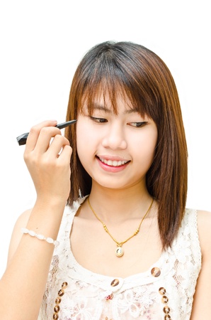 young cute girl using eye liner with her eye の写真素材