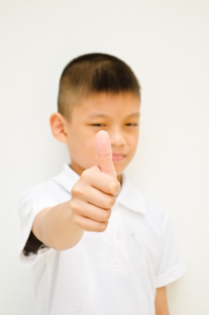angry asian boy show his thumb to someone on white backgroundの写真素材