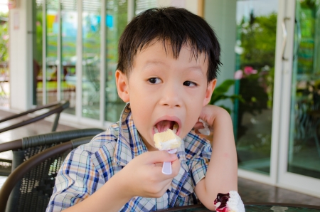 little asian boy eating cakeの写真素材