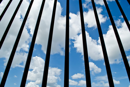 black iron fence with cloudy blue sky background