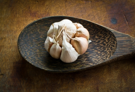 Garlic with peel on wood ladleの写真素材