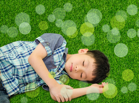 Asian boy sleeping on grass fieldの写真素材