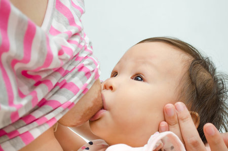 Asian mom breast feeding her baby girl