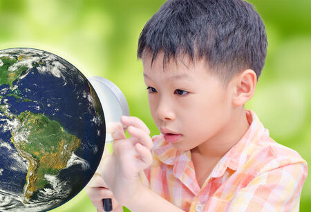 Asian boy looking map on globe via magnifying glass ,Elements of this image furnished by NASAの写真素材