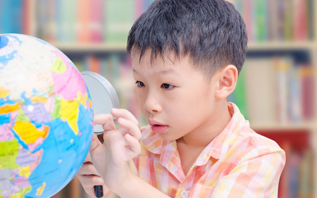 Asian boy looking at a globe in library