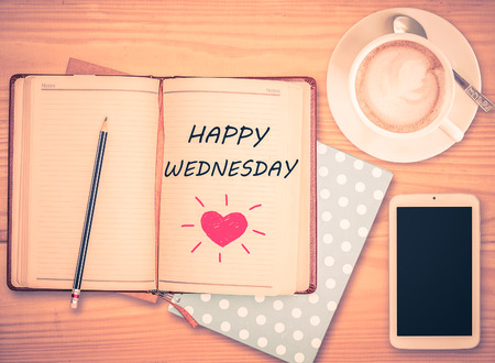 Happy Wednesday on notebook , pencil, smart phone and coffee cup with vintage filterの写真素材