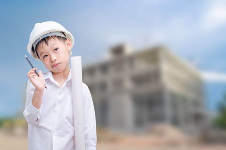 building, developing, construction and architecture concept -little boy in white helmet thinkingの写真素材
