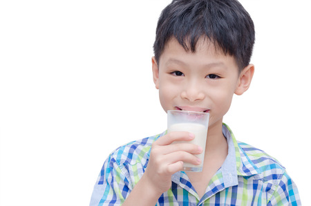 Asian boy smiles and holding a glass of milk over whiteの写真素材