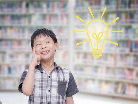 Young boy thinking with light bumb in libraryの写真素材