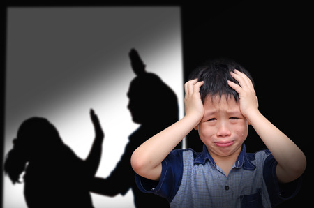 Asian boy crying with his parent fighting in backgroundの写真素材