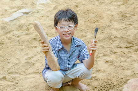 Young Asian boy with fake dinosaur bone at adventure parkの写真素材