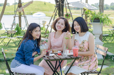 Three Asian girl eating cake and drink together at cafeの写真素材