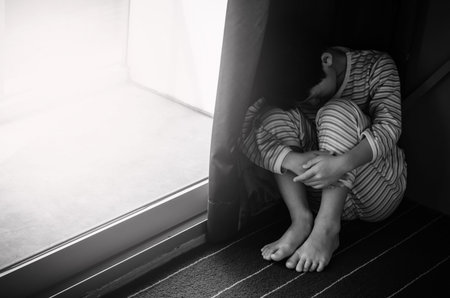 Young sad boy sitting on the floorの写真素材