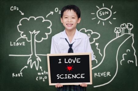 Asian schoolboy in uniform standing in front of chalkboardの写真素材