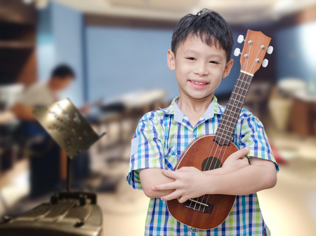 Asian boy with ukulele at music schoolの写真素材