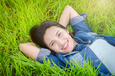 Beautiful asian girl lying on grass field and smilesの写真素材