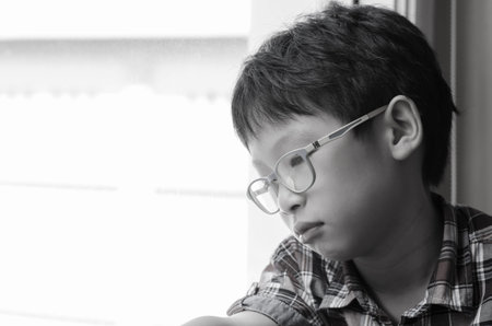 Sad Asian boy looking out of window