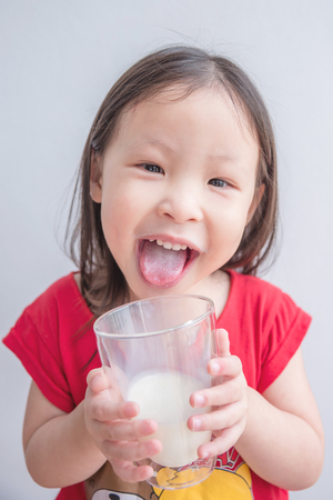 Little asian girl smiles after drinking milk from glassの写真素材