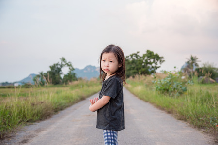 Sad little asian girl standing alone on streetの写真素材
