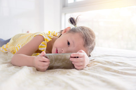Little asian girl playing game on cellphone