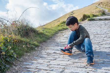 Young asian boy tying his shoelace by himselfの写真素材