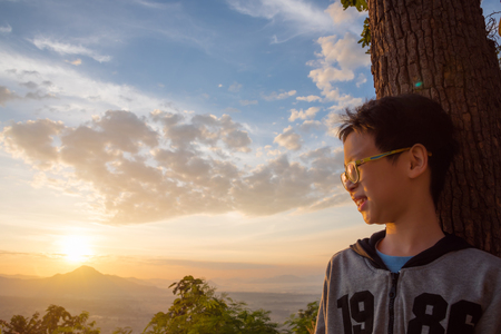 Boy watching sun rising on hillの写真素材
