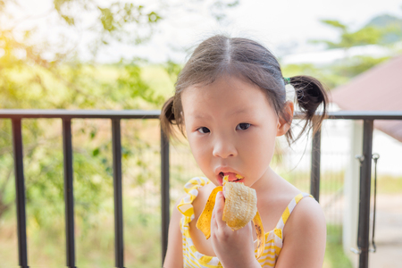 Little girl eating bananaの写真素材