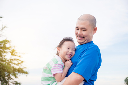 Asian father and his daughter smiling in parkの写真素材