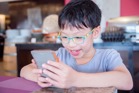 Young asian boy playing games on smart phoneの写真素材