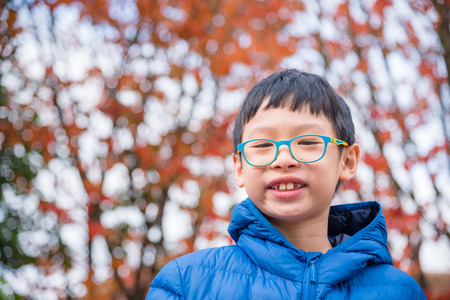 Asian boy smiling in autumn parkの写真素材