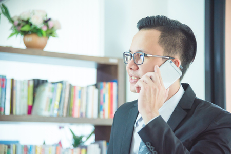 asian businessman talking with someone by mobile phoneの写真素材