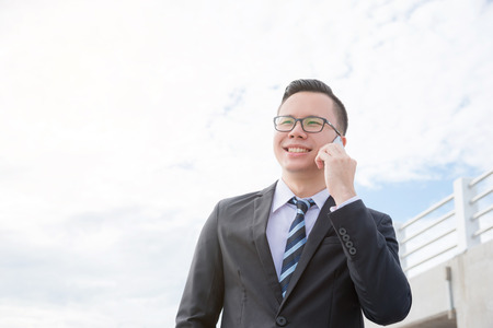 Businessman smiling while talking with someone via mobile phoneの写真素材