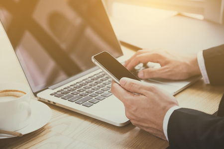 Hand of businessman using mobile phone and notebook computerの写真素材