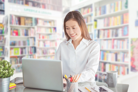 Beautiful university student working with laptop computer in libraryの写真素材