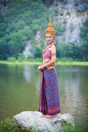 Beautiful asian woman wearing Thai ancient traditional costume standing near by the river and smilesの写真素材
